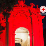 Porta Lambertina illuminata di rosso per la giornata mondiale della Croce Rossa e della Mezzaluna Rossa